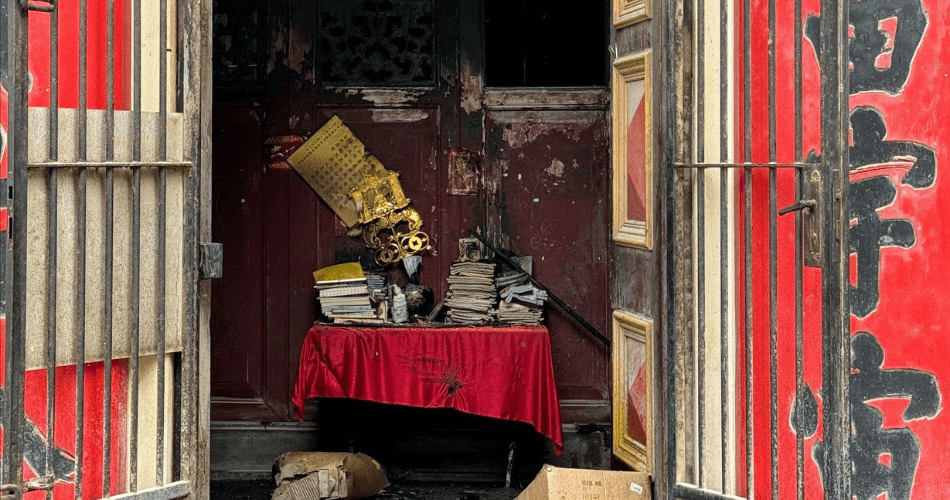 Fire‑damaged entrance of the See Yup Temple, with charred timber, burnt debris, and blackened structural elements visible after the blaze